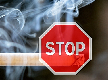 Stop-Schild über qualmender Zigarette